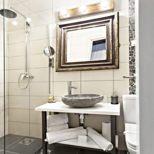 Modern contemporary interior bathroom with sink and mirror, glass walk in shower with marble tile surround